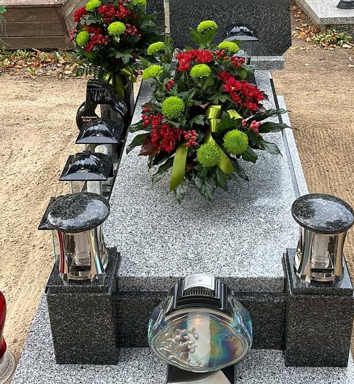 Grób przygotowany na Wszystkich Świętych: kompozycja z chryzantem i zapalone znicze